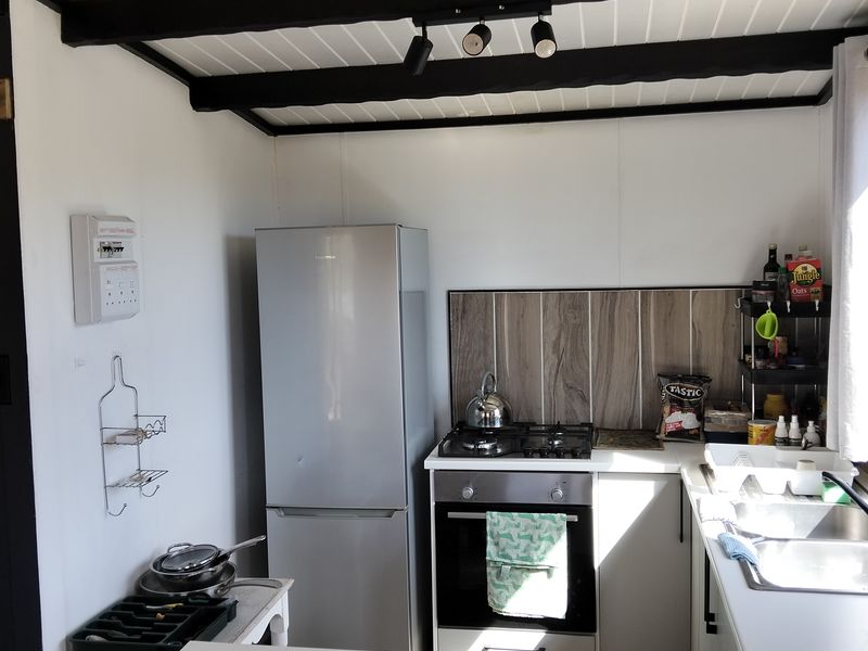 Compact kitchen featuring a gas hob, built-in oven, stainless steel sink, and exposed ceiling beams with a functional layout.