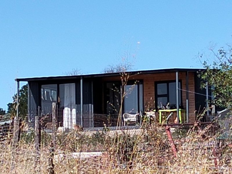 A modern single-story dwelling featuring a combination of metal and timber cladding with large sliding glass doors opening onto a covered patio area.