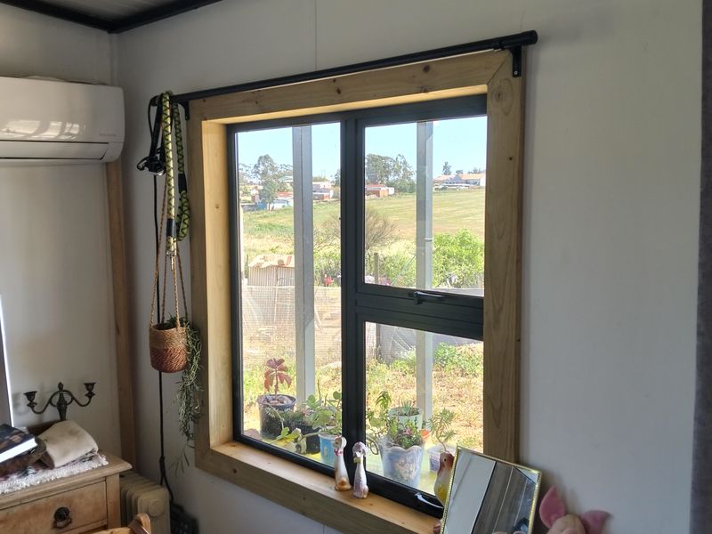 A bedroom featuring exposed ceiling beams, a split-system air conditioner, and a timber-framed window with views of the surrounding landscape.
