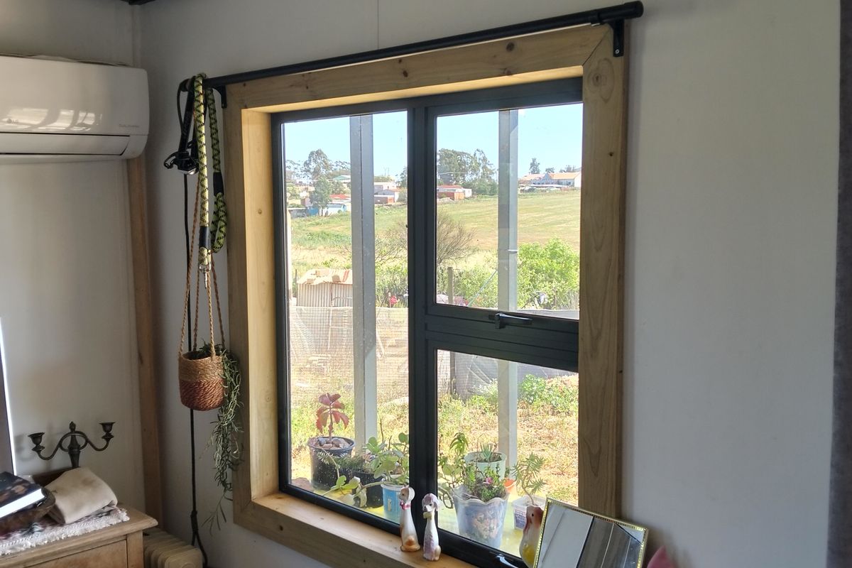 A bedroom featuring exposed ceiling beams, a split-system air conditioner, and a timber-framed window with views of the surrounding landscape.