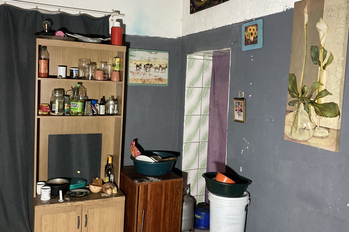 A small kitchen area featuring a tiled wall section and painted walls, currently used for storage and food preparation.