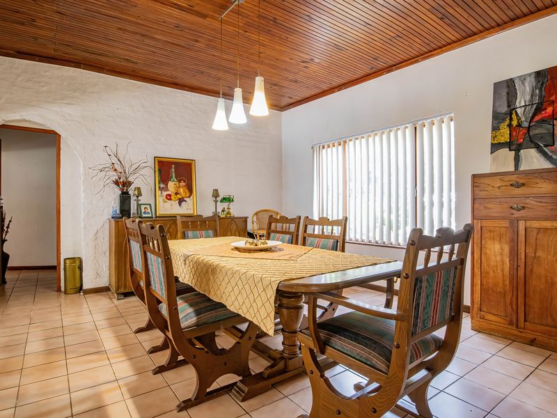 A dining room featuring a warm timber tongue and groove ceiling, ceramic tiled flooring, and an arched entryway leading to the rest of the home.