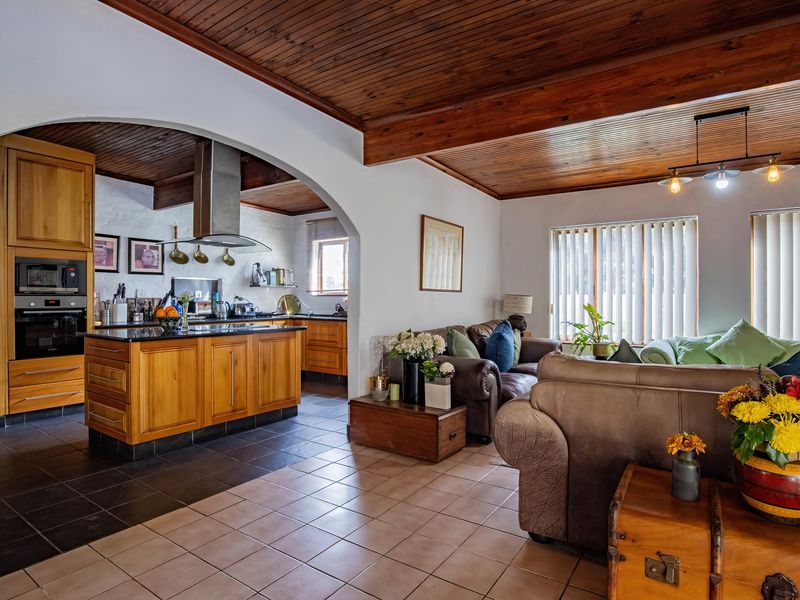 Spacious open-plan living area featuring a well-appointed kitchen with wooden cabinetry, granite countertops, and a warm timber-clad ceiling with exposed beams.