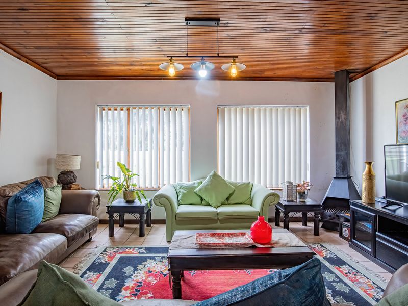 A cozy living room featuring a wood-paneled ceiling, tiled flooring, and a prominent freestanding fireplace, offering a warm and inviting atmosphere.