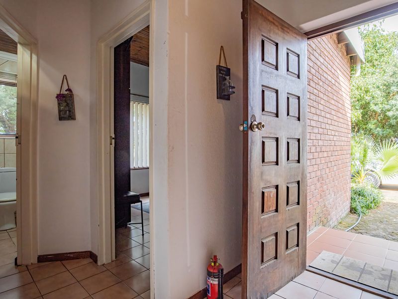 Entrance area featuring a solid wooden door, ceramic tiled flooring, and direct access to an exterior brick-walled patio space.