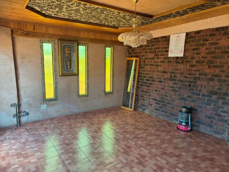 A spacious living area featuring exposed brickwork, timber ceiling detailing, and unique vertical stained glass windows, offering a distinct retro aesthetic.