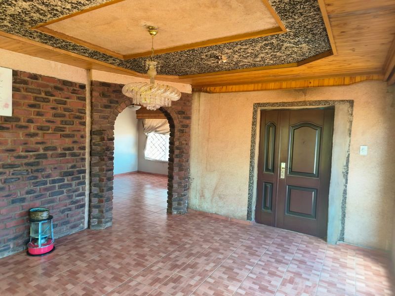 Entrance foyer featuring a brick archway, tiled flooring, and a decorative ceiling, offering a distinct architectural layout ready for modernization.