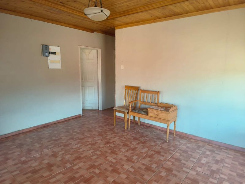 A living area featuring a timber-clad ceiling, tiled flooring, and a wall-mounted electrical distribution board.