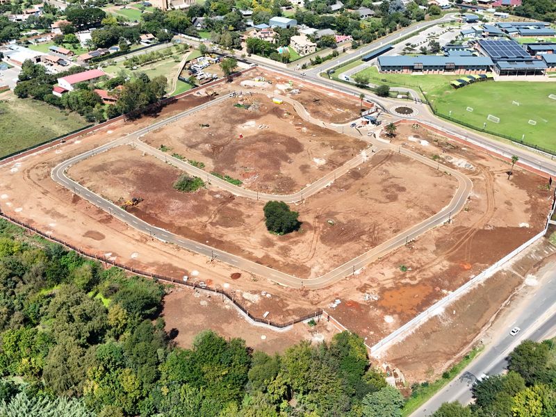 Aerial view of a vacant residential development site featuring established perimeter fencing, internal paved road infrastructure, and street lighting.
