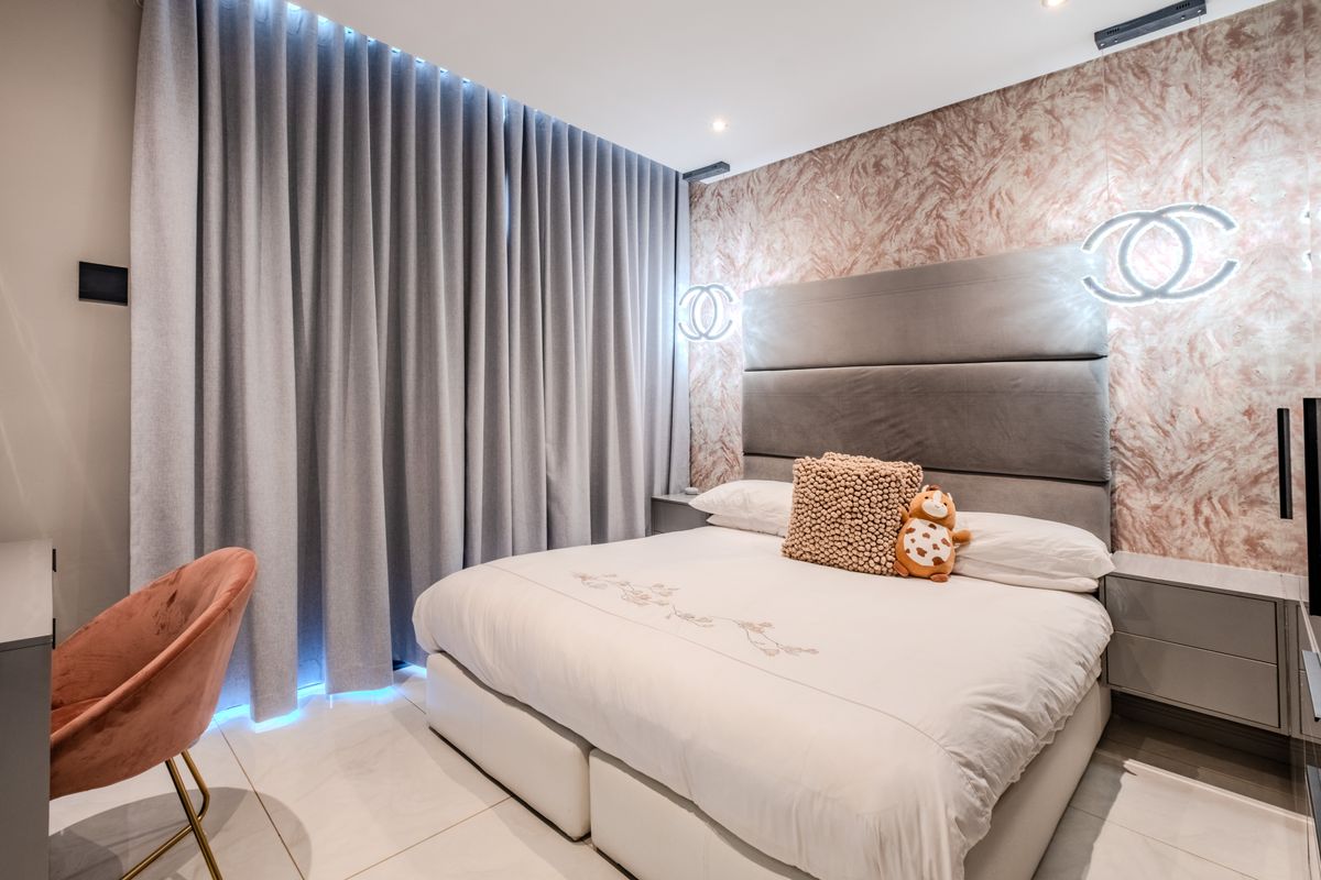 Modern bedroom featuring a marble-effect feature wall, recessed ceiling lighting, tiled flooring, and integrated bedside cabinetry.