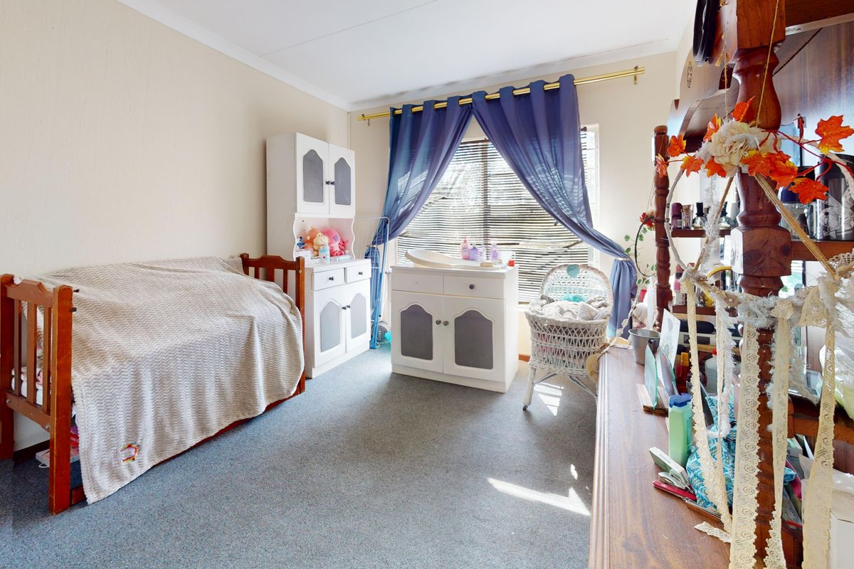A functional bedroom featuring carpeted flooring, venetian blinds, and a curtain rod, providing a neutral base for personalization.