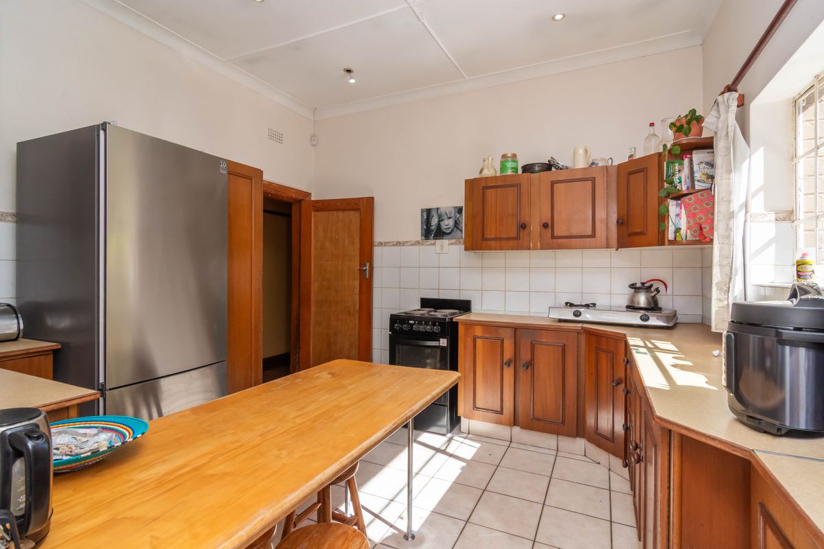A functional kitchen featuring wooden cabinetry, tiled flooring, a built-in stove, and a breakfast counter, offering a traditional layout with ample storage space.
