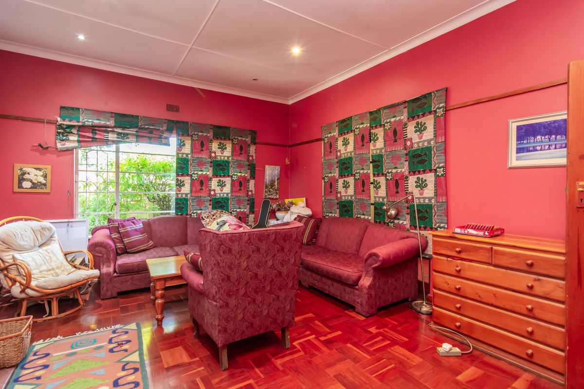 A living room featuring traditional parquet flooring, recessed downlighting, and large windows with security bars.