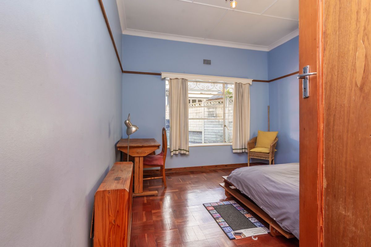 A bedroom featuring original parquet flooring, picture rails, and a large window providing natural light.