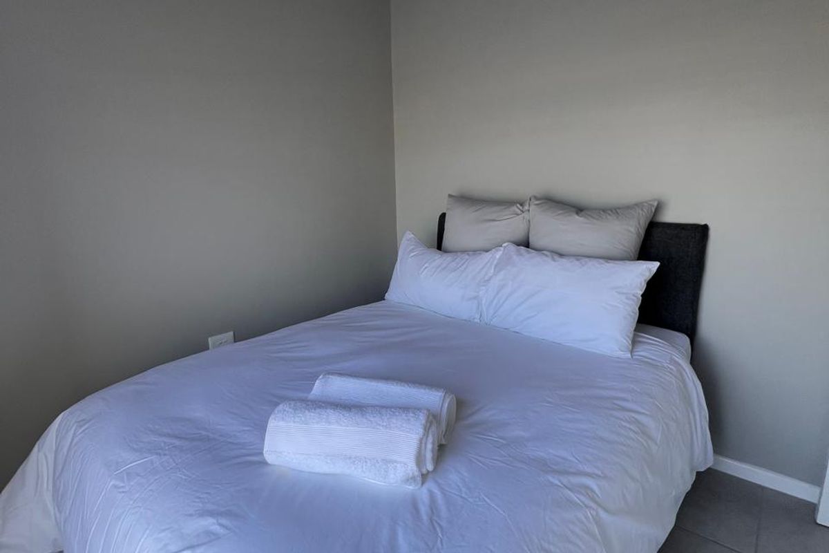 A simple bedroom featuring neutral wall tones and tiled flooring, providing a clean and functional space.
