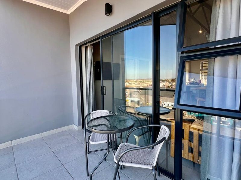 A modern covered balcony featuring tiled flooring, large sliding glass doors, and contemporary exterior lighting, offering a seamless transition to outdoor living.
