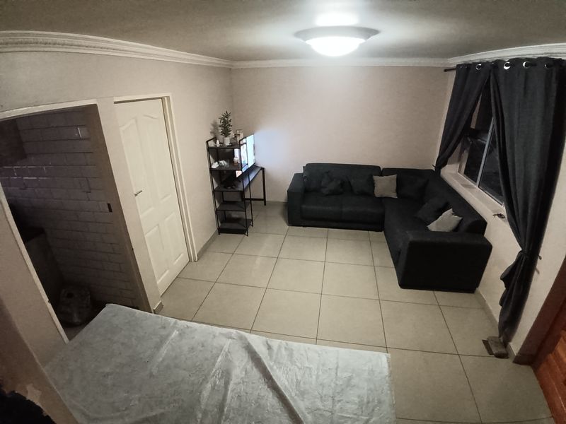 A living room featuring tiled flooring, ceiling cornice, and a central light fixture, providing a functional space for relaxation.