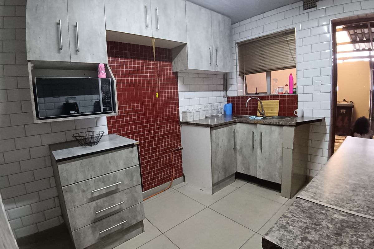 Functional kitchen featuring grey cabinetry, subway tile backsplash, laminate countertops, and a built-in microwave space.