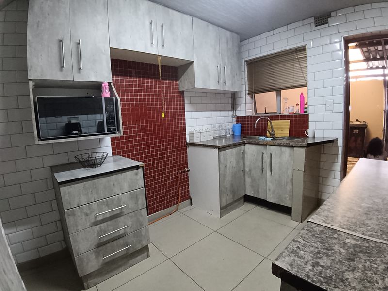 Functional kitchen featuring grey cabinetry, subway tile backsplash, laminate countertops, and a built-in microwave space.