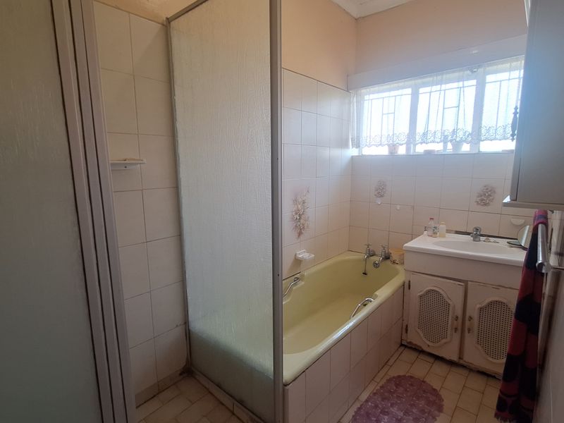 A dated bathroom featuring a shower enclosure, a bathtub, and a vanity cabinet with a washbasin, finished with tiled walls and flooring.