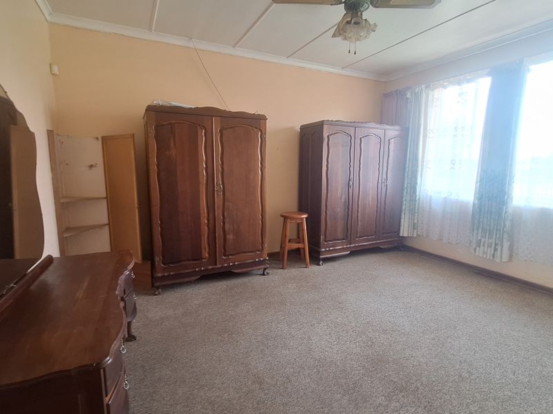 A spacious bedroom featuring carpet flooring and a ceiling fan, offering a blank canvas for renovation and modernization.