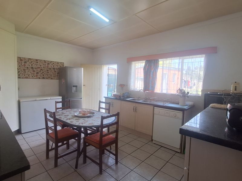 A functional kitchen featuring tiled flooring, built-in cabinetry, and a double sink, with direct access to the exterior.