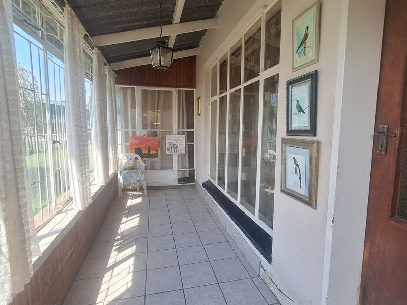 A sun-drenched enclosed patio featuring tiled flooring, large glass windows, and exposed beam ceiling, offering a bright and versatile transition space.