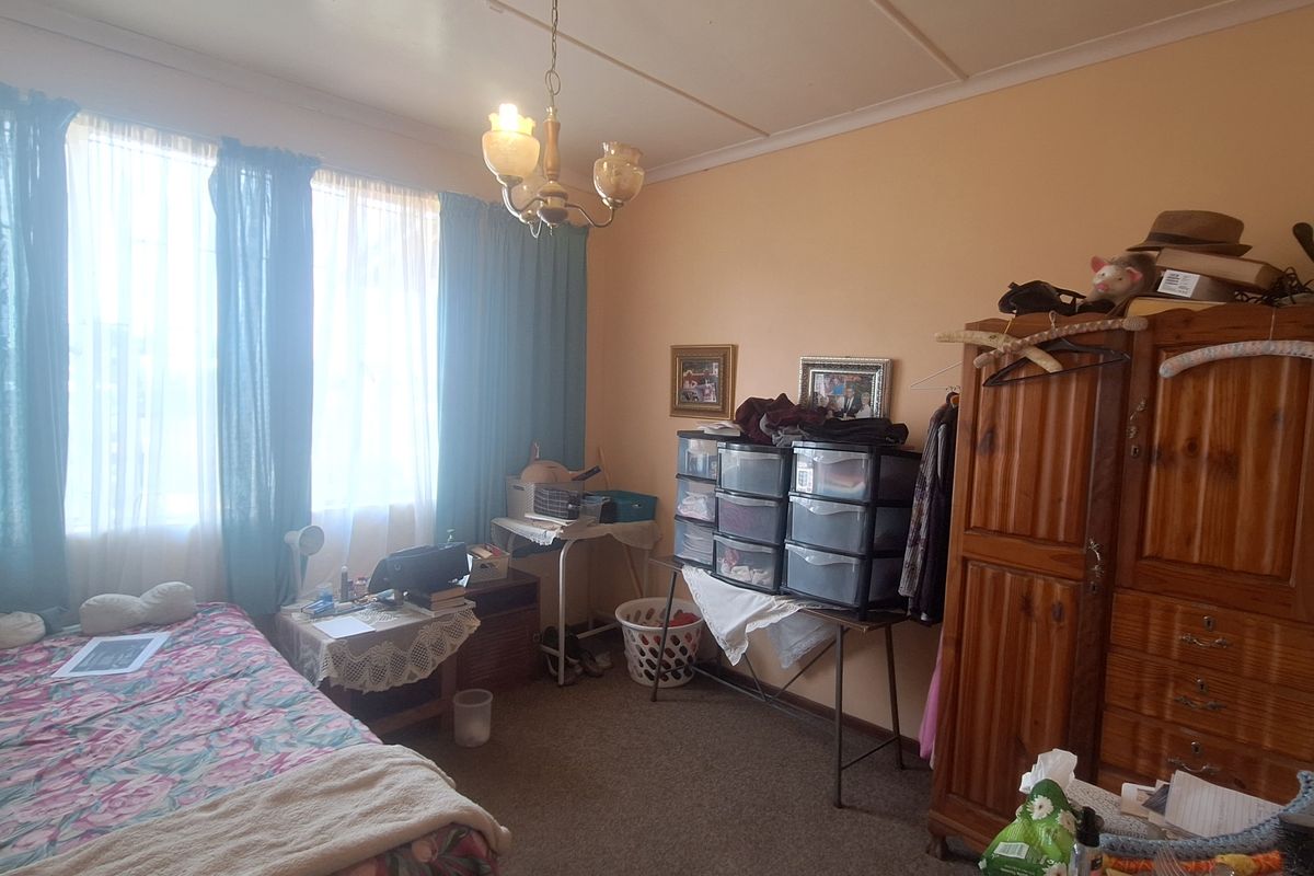 A bedroom featuring carpeted flooring and a central ceiling light fixture, currently showing signs of wear and dated finishes.