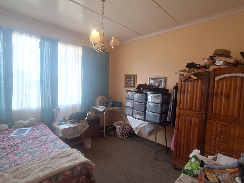 A bedroom featuring carpeted flooring and a central ceiling light fixture, currently showing signs of wear and dated finishes.