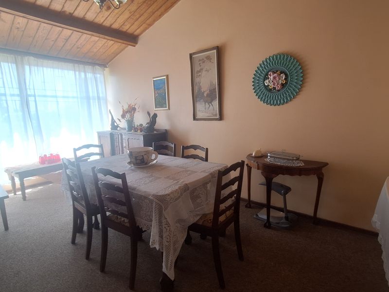 A dining room featuring a high exposed timber beam ceiling and large window, providing a traditional aesthetic with potential for modern updates.