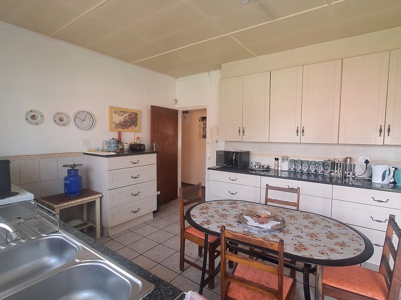 A functional kitchen featuring granite countertops, double bowl sink, and ample built-in cabinetry, with tiled flooring and a standard ceiling finish.