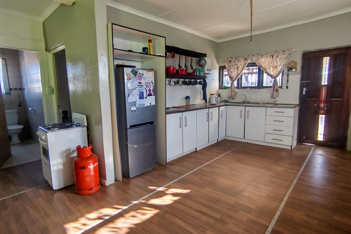 A functional kitchen featuring white cabinetry, laminate flooring, and a gas stove, with an adjacent view into a bathroom area.