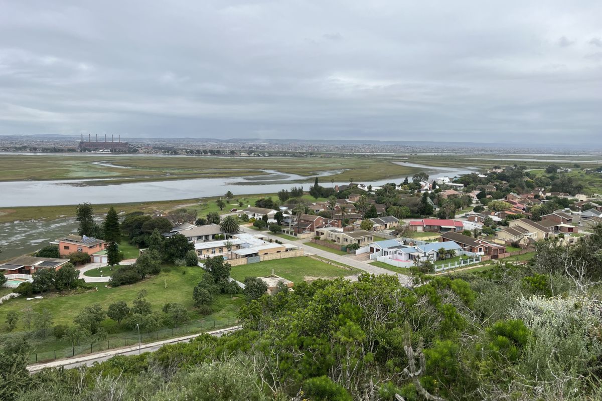 An elevated aerial view overlooking a residential neighborhood situated near coastal wetlands and natural landscape.
