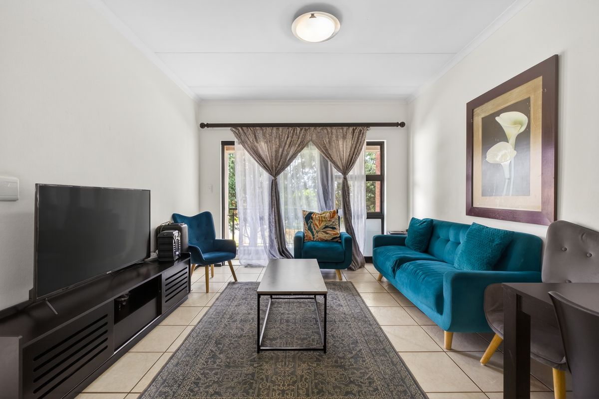 A bright and well-maintained living room featuring tiled flooring and a large sliding glass door that provides natural light and access to the outdoors.