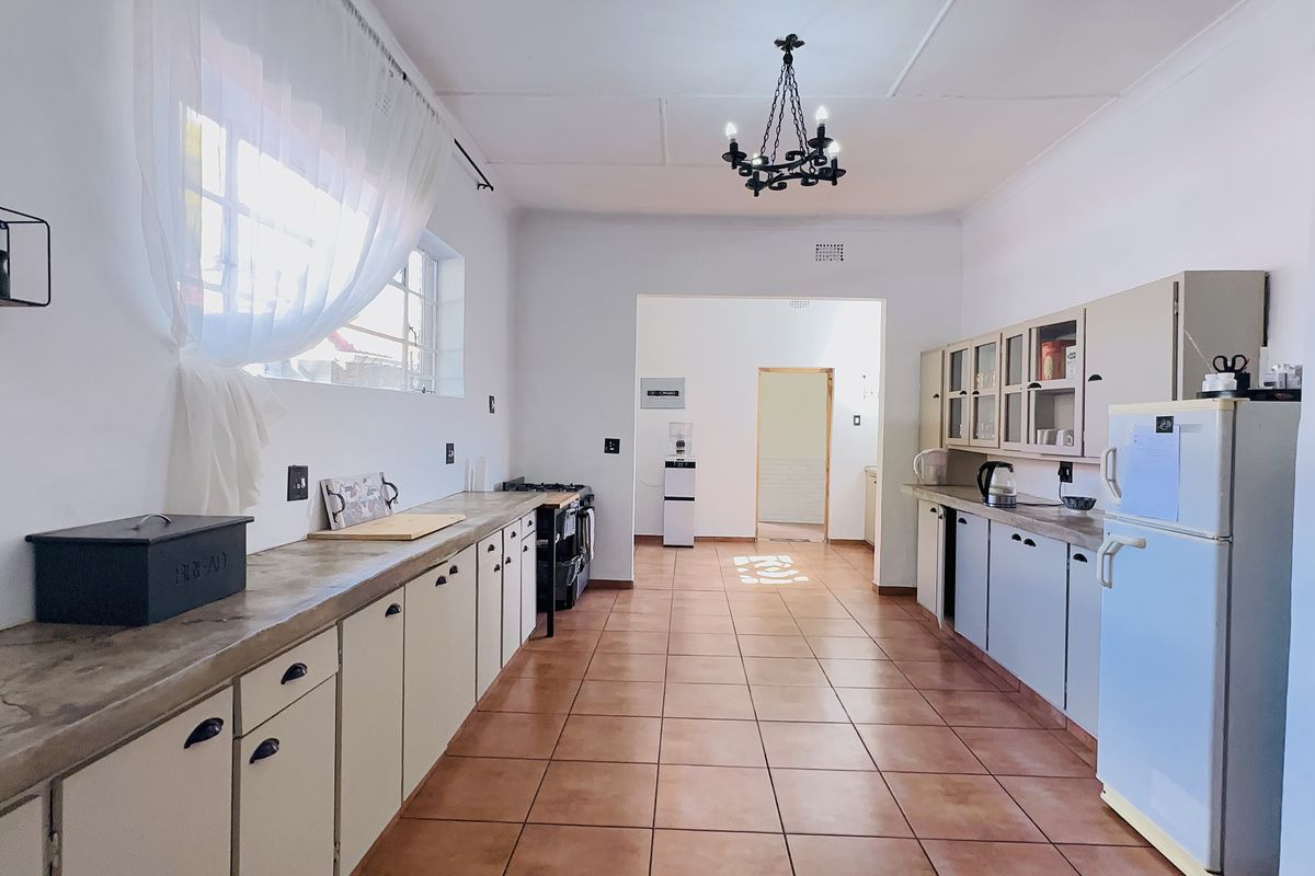 Spacious kitchen featuring extensive built-in cabinetry, tiled flooring, and a central chandelier, offering a functional layout with ample counter space.