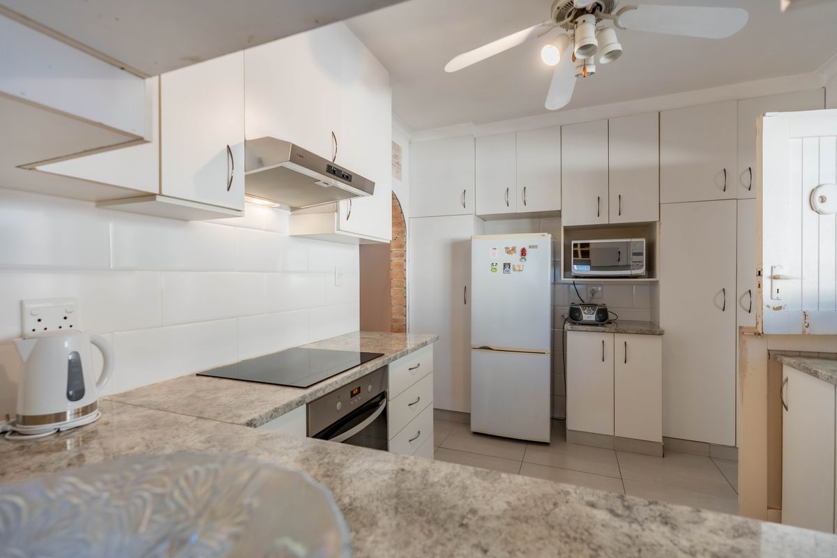 Functional kitchen featuring white cabinetry, stone-look countertops, tiled backsplash, built-in oven, electric cooktop, and an integrated extractor fan.