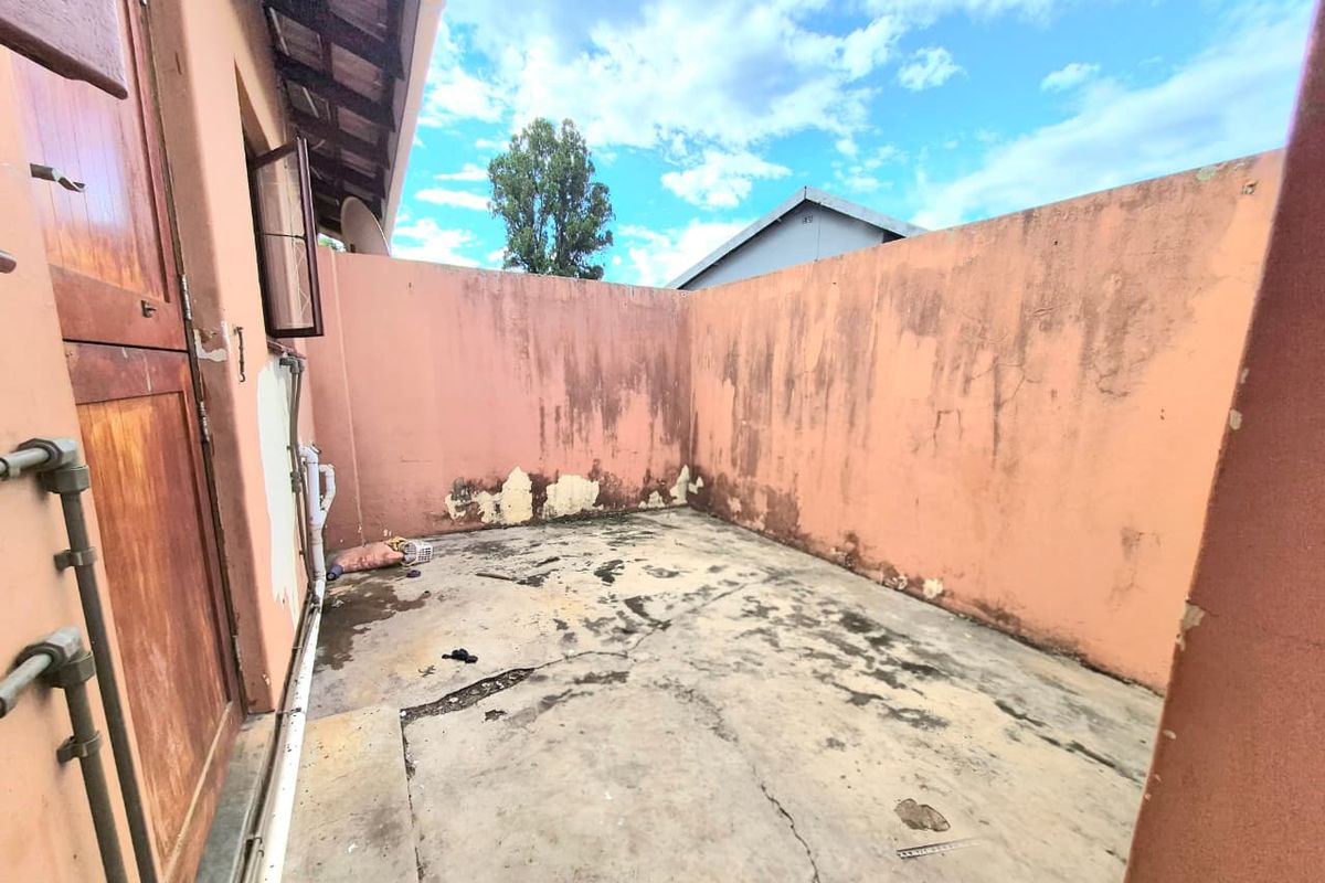 A private rear courtyard area featuring concrete flooring and boundary walls, currently requiring maintenance and cosmetic repairs to the wall surfaces and floor.