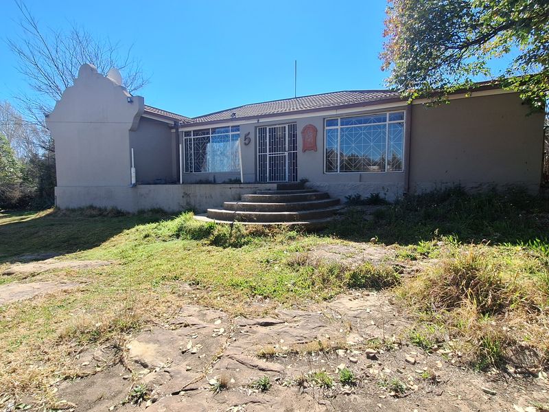 Front elevation of a single-story house featuring a gabled parapet, security gates, and concrete steps leading to the entrance.