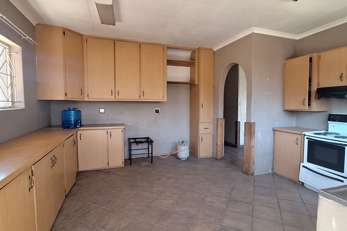 A spacious kitchen featuring laminate cabinetry, tiled flooring, and a freestanding stove, offering a functional layout with potential for modern updates.