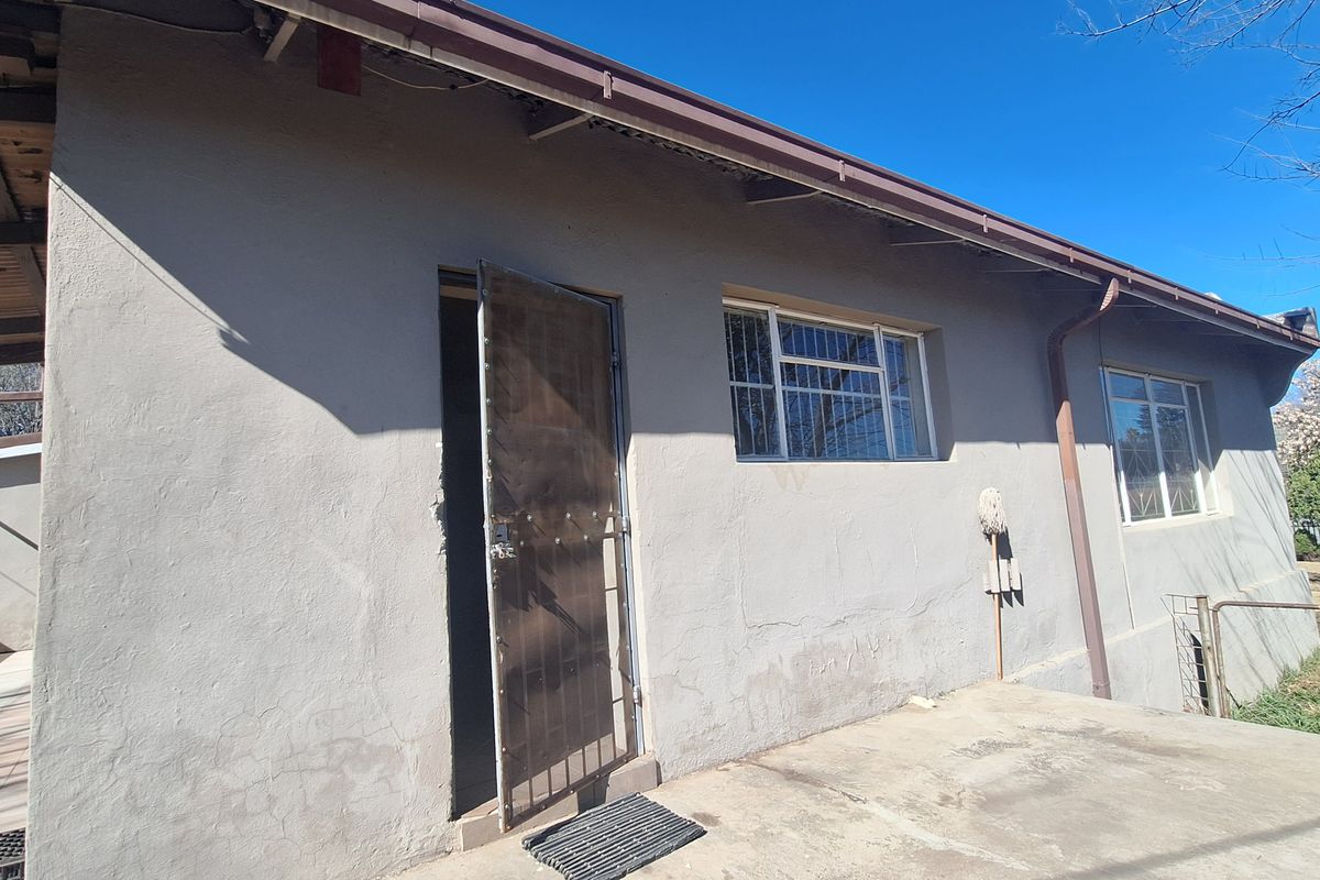 Rear exterior view of the house featuring a concrete patio, security gate, and security bars on the windows.