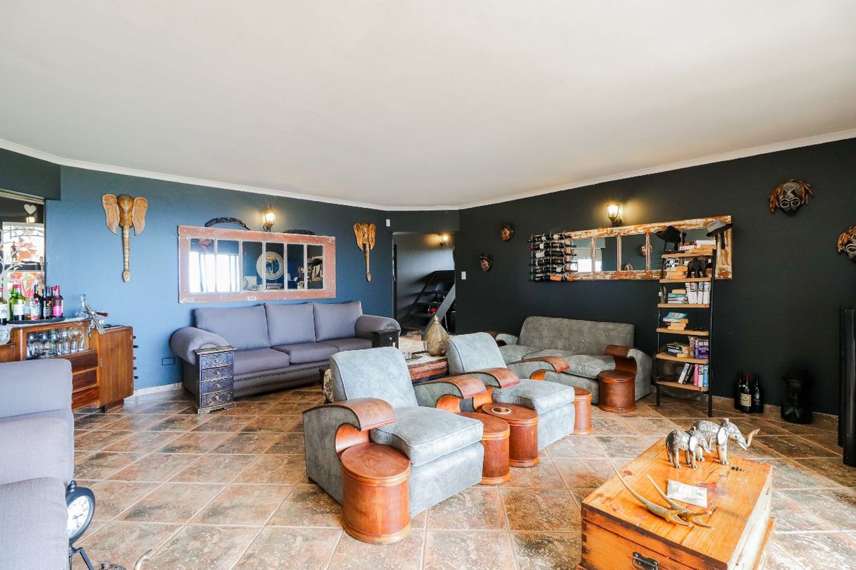 Spacious living room featuring dark painted walls, tiled flooring, and wall-mounted lighting fixtures.