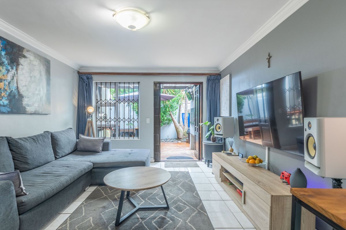 A well-maintained living room featuring tiled flooring, crown molding, and direct access to an outdoor patio area through a secure sliding door.