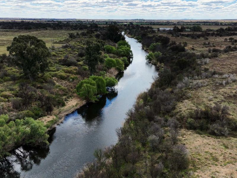 An aerial view of a river flowing through the rural landscape, showcasing the natural surroundings and water frontage of the property.