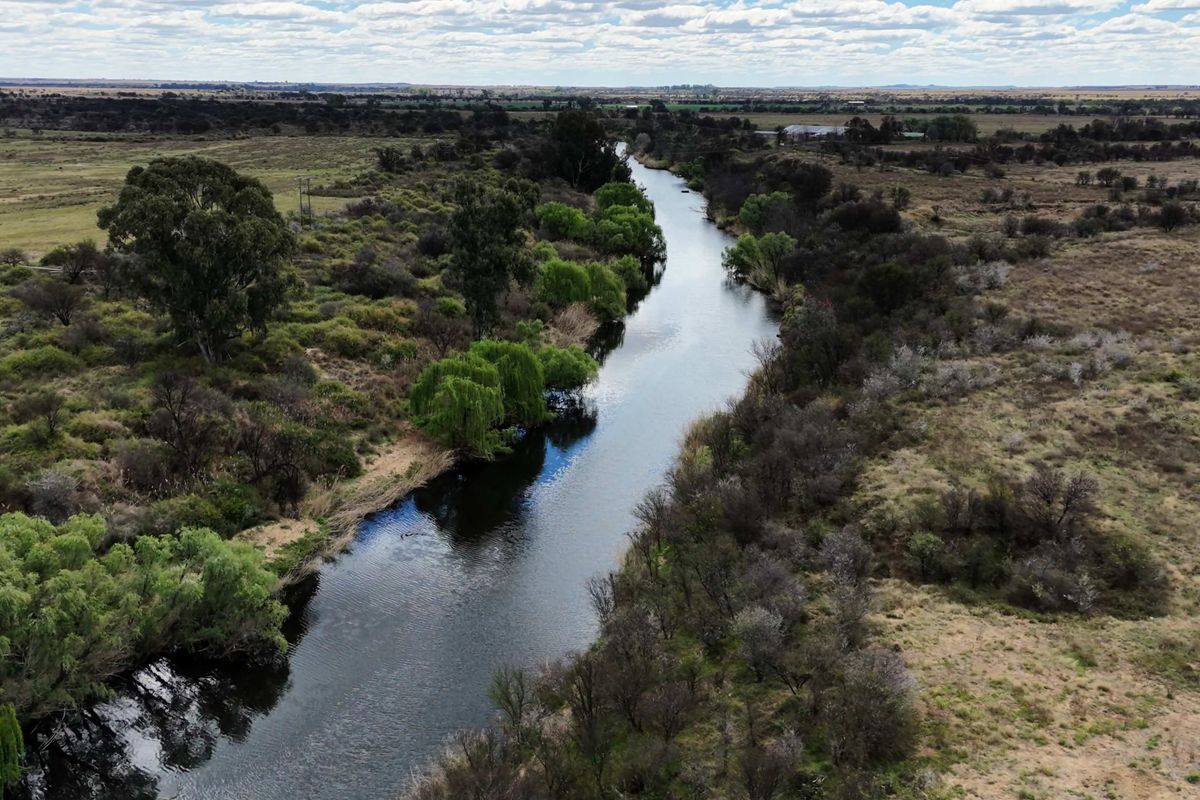 An aerial view of a river flowing through the rural landscape, showcasing the natural surroundings and water frontage of the property.