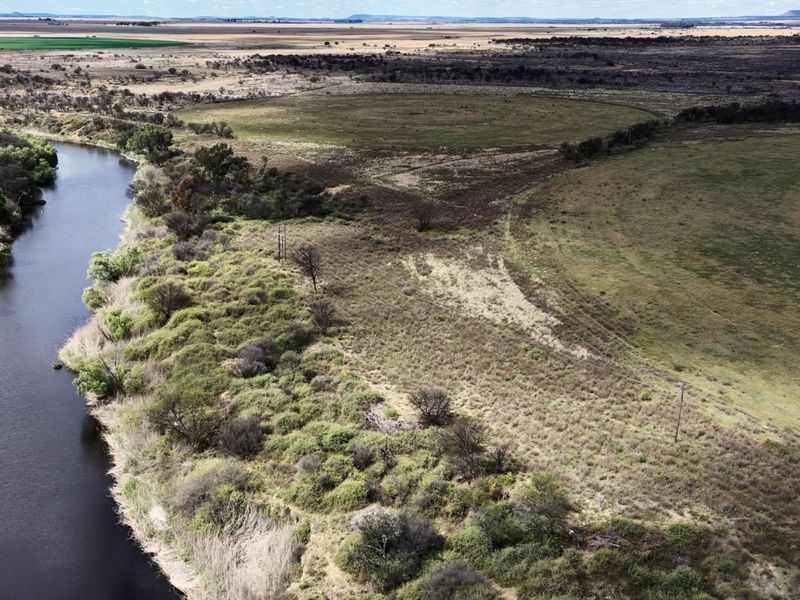 An aerial view of the farm property showcasing extensive grazing land and direct river frontage.