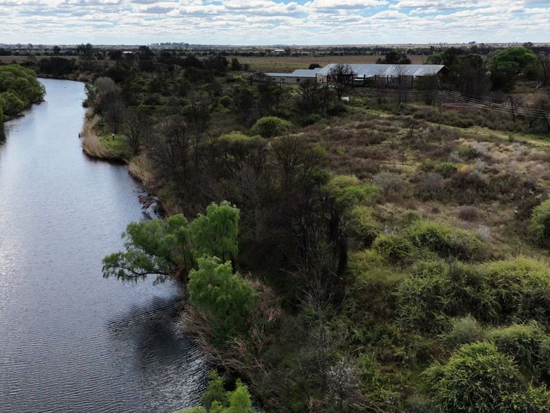 An aerial view of the farm property showcasing extensive river frontage and natural landscape surrounding the main farm buildings.