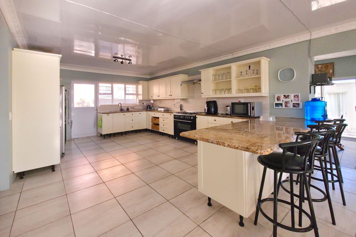 Spacious kitchen featuring granite countertops, ample built-in cabinetry, a central island, and a gas stove, offering a functional layout for cooking and dining.