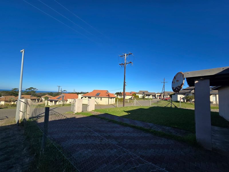 A street-level view of the property exterior showing the paved driveway, perimeter fencing, and surrounding residential neighborhood.