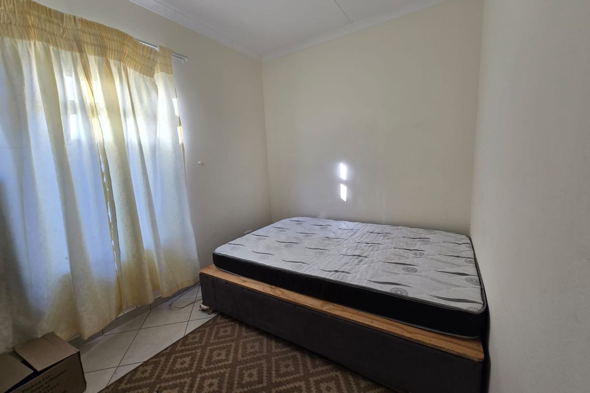 A simple bedroom featuring tiled flooring and cove cornice detailing, providing a functional space ready for personalization.