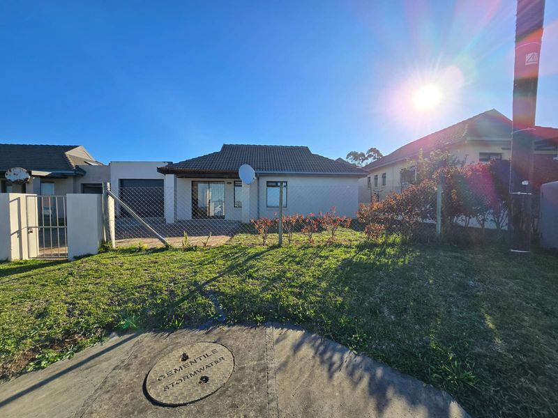 Front view of a single-story residential house featuring a tiled roof, attached garage, and a front garden area with chain-link fencing.